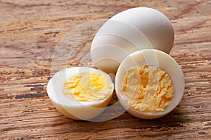 Boiled egg cutout and raw egg with shell on wooden background