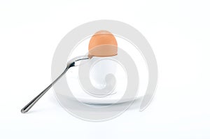 Boiled egg in egg cup with spoon, on white background.