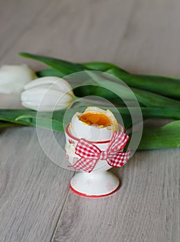 Boiled egg in egg cup with tulips.