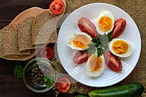 Boiled egg and fresh tomato, black bread - light diet breakfast.