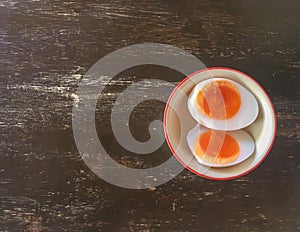 Boiled eggs are divided into two pieces in a cup on a wooden table.