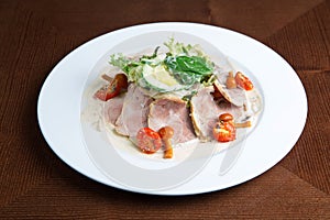 Boiled eggs with smoked ham and vegetables on white plate