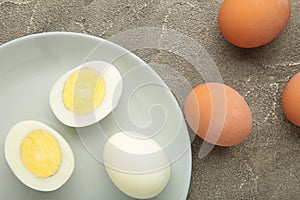 Boiled eggs in white ceramic plate on grey background