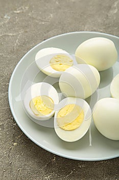 Boiled eggs in white ceramic plate on grey background. Vertical photo