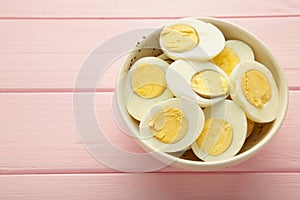 Boiled eggs in white ceramic plate on pink background. Space for text