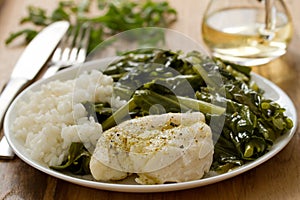 Boiled fish with rice and kale on white plate