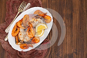 Boiled fish with shrimps and lemon on white dish