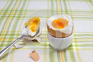 Boiled fresh smash broken egg for the breakfast on the porcelain stand for eggs. Broken beige hen egg and pieces of shells, bright