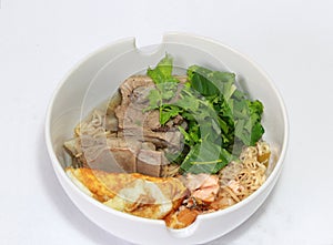 Boiled instant noodles with pork rip, fried egg, fish meat and green vegetable in the white bowl.