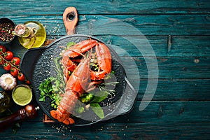 Boiled lobster with vegetables on a black stone plate. Seafood. Top view.