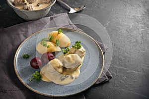 Boiled meatballs in Germany called Koenigsberger Klopse in a white bechamel sauce with capers, potatoes and beetroot on a blue