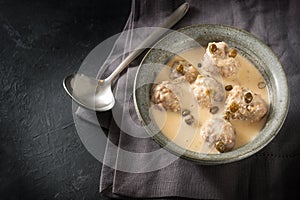 Boiled meatballs in a white bechamel sauce with capers, called Koenigsberger Klopse, traditional Polish and German dish in bowl on photo