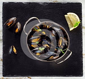 Boiled mussels in cooking dish on dark background.