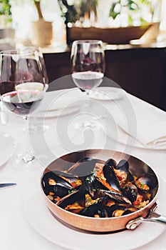 Boiled mussels in copper cooking dish on white background close up.