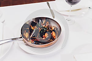 Boiled mussels in copper cooking dish on white background close up.