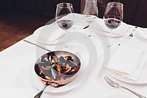 Boiled mussels in copper cooking dish on white background close up.