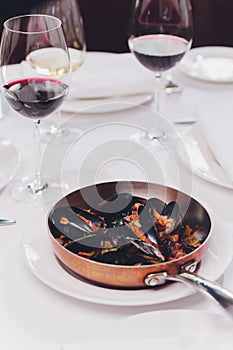 Boiled mussels in copper cooking dish on white background close up.