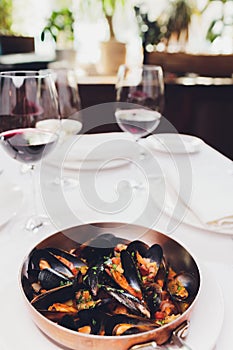 Boiled mussels in copper cooking dish on white background close up.