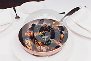 Boiled mussels in copper cooking dish on white background close up.