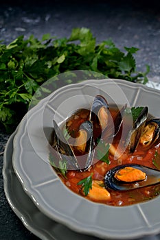 Boiled mussels soup on a grey plate