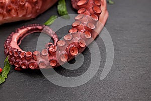 Boiled octopus on black stone background close-up.