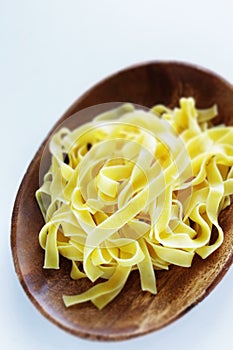 Boiled pasta fettuccine for cooing on wooden plate