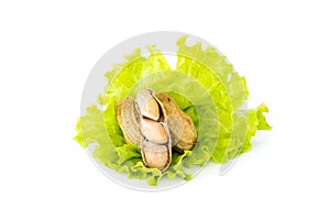 Boiled peanuts over green vegetable on white background