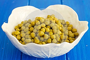 Boiled peas on white bowl on blue background