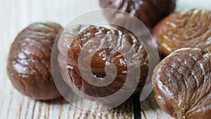 Boiled and peeled chestnuts , closeup studio macro photo on white wooden table photo