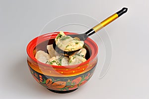 Boiled pelmeni in khokhloma painted russian wooden bowl with spoon