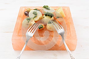 Boiled potatoes and carrots with green chimichurri sauce and vintage forks served on square pink hymalayan salt block