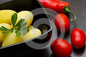 Boiled potatoes with chili peppers and tomatoes on a dark background