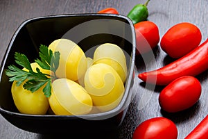 Boiled potatoes with chili peppers and tomatoes on a dark background