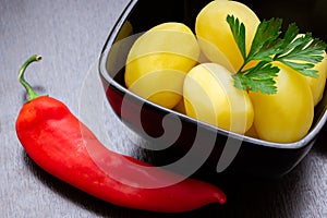 Boiled potatoes with chili peppers and tomatoes on a dark background