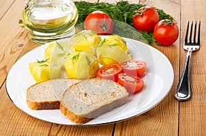 Boiled potatoes with tomato, bread in plate, bottle of vegetable oil, dill, tomatoes, fork on table