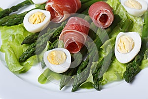Boiled quail eggs with ham and asparagus close-up top view