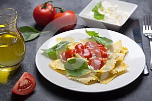 Boiled ravioli with basil, cheese and tomato sauce on a black background photo