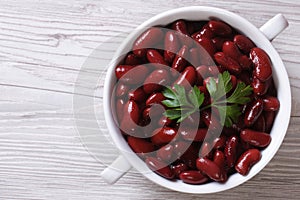 Boiled red kidney beans in a bowl closeup on wooden top view