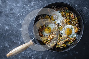 Boiled rice with fried eggs, pumpkin, peppers, carrots and onions in a cast iron pan, closeup. Food background. Healthy food