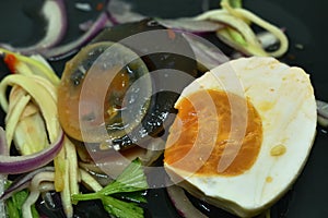 Boiled salty and black preserved egg half cut with slice ginger salad on plate