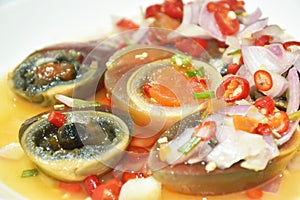 boiled salty black preserved egg half cut with slice shallot and chili salad on plate