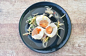 Boiled salty egg half cut with slice ginger salad on plate