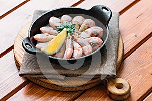 Boiled shrimp with lemon and parsley on a wooden table