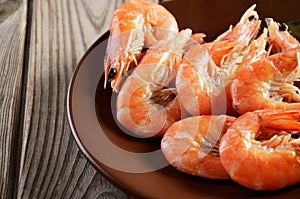 Boiled shrimp on a plate on a wooden background close-up