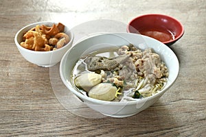 boiled slice and chop pork with meatball in clear soup on bowl eat couple baking pork skin cracker in cup