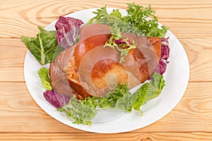 Boiled-smoked pork knuckle on the lettuce leaves on dish