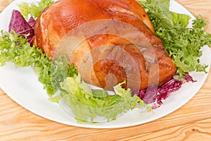 Boiled-smoked pork knuckle on the lettuce leaves on dish