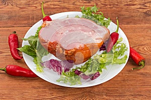 Boiled-smoked pork knuckle on the lettuce leaves on dish