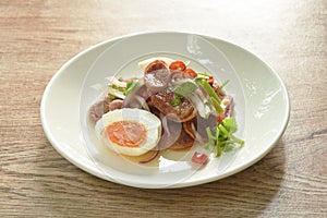 Boiled spicy salty egg half cut with Chinese pork sausage topping shallot salad on plate