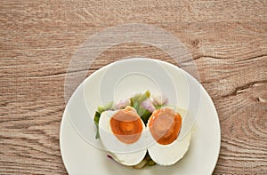 Boiled spicy salty egg half cut with slice shallot and chili salad on plate